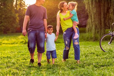 Mutlu aile-genç gülümseyen çocuk parkı ebeveynler ile yürüme