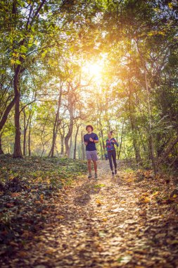 fitness, spor, eğitim ve yaşam tarzı kavramı genç çift ormanda koşu