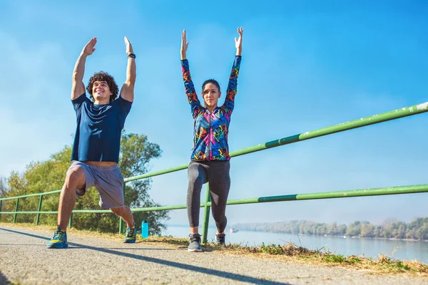 young fitness man and woman stretching in the park. Young couple warming up in morning