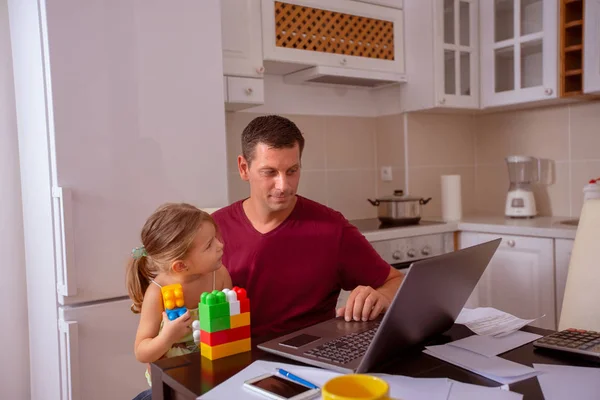 busy male working with computer while looking after his daughter