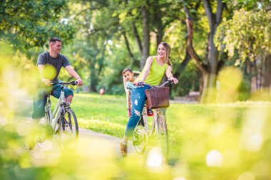 Mutlu etkin baba ve anne ile çocuk Bisiklet park eğleniyor. Mutlu bir aile