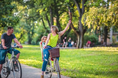 Mutlu etkin baba ve anne ile çocuk parkında eğleniyor Bisiklet.