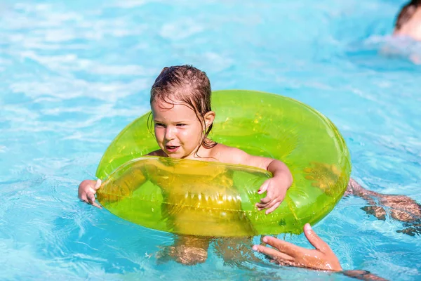 Glückliches Mädchen im Pool bei grünem Lebensretter, der schwimmen lernt — Stockfoto