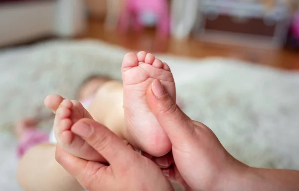 Nyfödda baby fötter i händerna på mor — Stockfoto