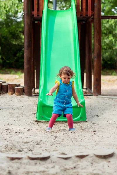 Glückliche Kindheit - Mädchen stürzt Rutsche auf Spielplatz hinunter — Stockfoto