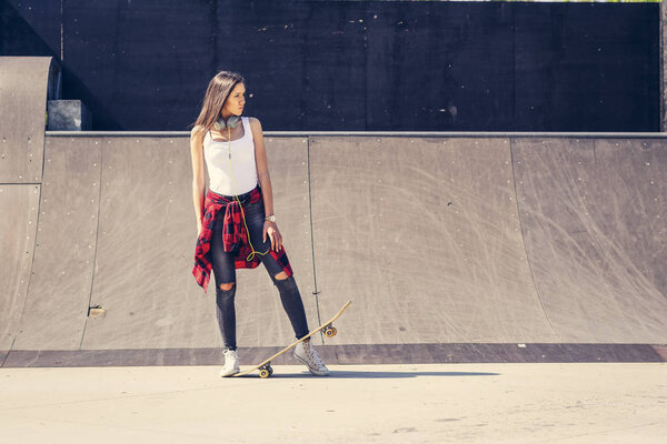 Cute girl holding skateboard in skate park