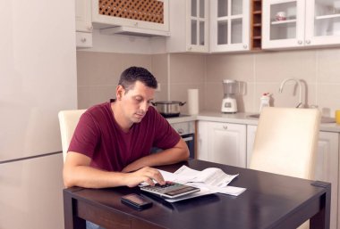 evde giderleri hakkında hesap yapıyor iş adamı,