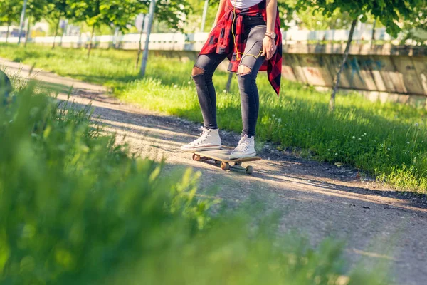 Woman skateboarder - sporty legs skateboarding in park