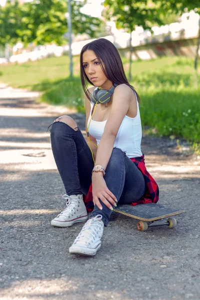 Sportig tjej sitter på skateboard. Utomhus, urban livsstil — Stockfoto