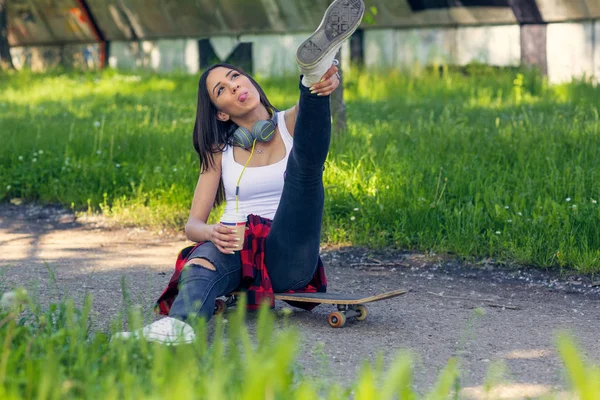 Lycklig skateboardåkare kvinna sitter på skateboard och dricka Coffe — Stockfoto