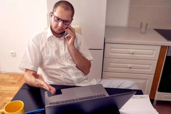 Finanças homem trabalhando e falando em seu telefone em casa — Fotografia de Stock