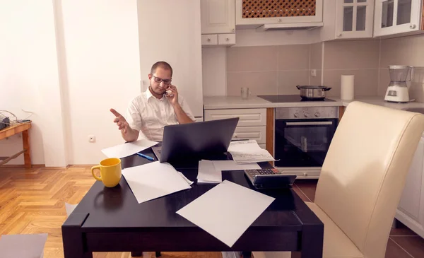 Hombre de finanzas trabajando y hablando por teléfono en casa — Foto de Stock
