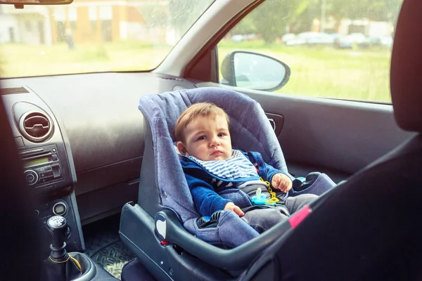 Fotelik samochodowy dla bezpieczeństwa. Uśmiechnięty chłopak siedzi w samochodzie w fotelu bezpieczeństwa. Obraz Stockowy