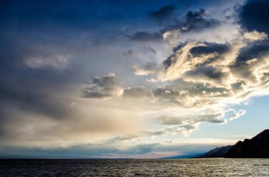 Fırtınalı bulutlar dramatik gökyüzü moody koyu ve başgösteren yansıtan su genelinde üzerinden günbatımı