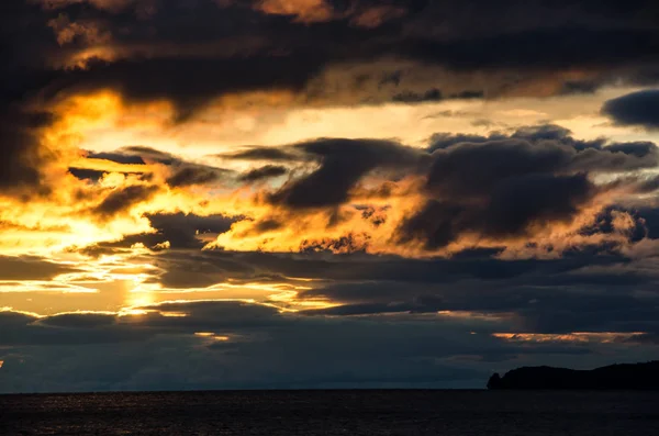 Закат над бурными облаками над водой, отражающими темное и надвигающееся драматическое небо — стоковое фото