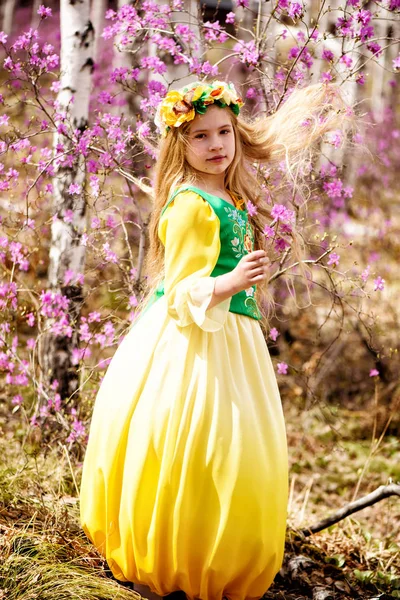 Ein Kind steht zwischen Ledum und Birke in grün-gelbem Kleid, lächelt und fliegt — Stockfoto