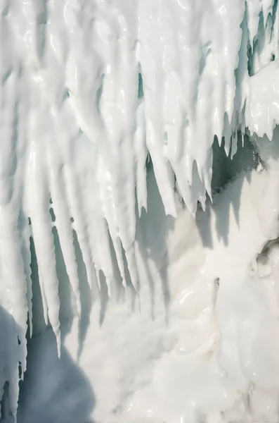 Backdrop of ice stalactites with a crack. White icicles in a frozen ice wall. — Stock Photo, Image