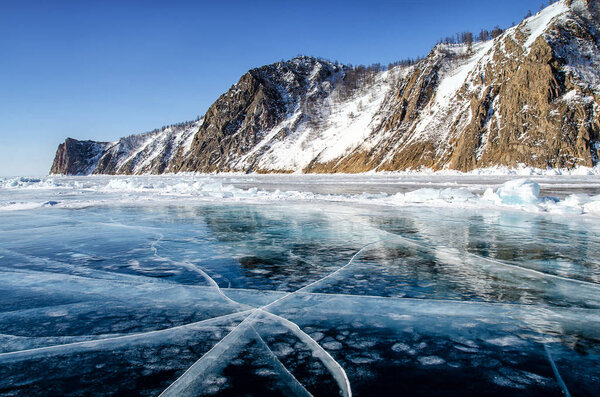 View of beautiful drawings on ice from cracks and bubbles of deep gas on surface of Baikal lake in winter, Russia