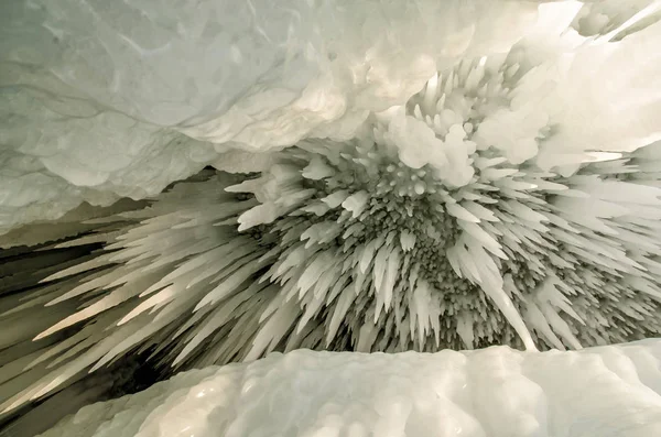 Kulisse von Eisstalaktiten mit einem Riss. weiße Eiszapfen in einer gefrorenen Eiswand. — Stockfoto
