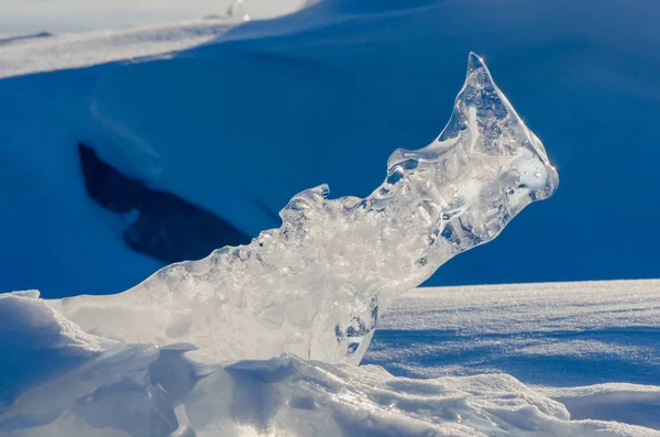 Transparent piece of ice on the snow near frozen Baikal lake