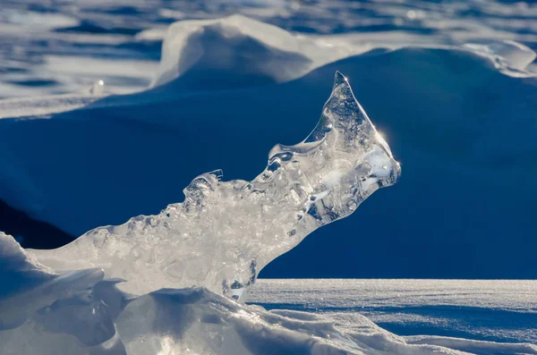 Transparent piece of ice on the snow near frozen Baikal lake