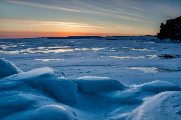 Walking in winter on the ice and snow texture. Sunset and silhouettes of people — Stock Photo, Image