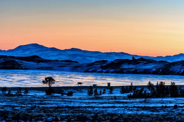 Amazimg orange view of the ice and the rising sun over the mountains, lake Baikal