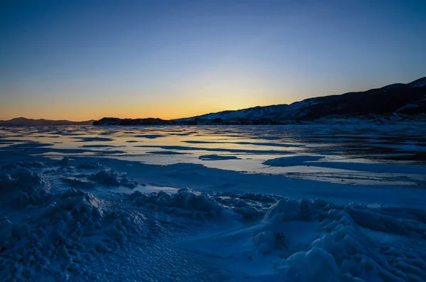 Buz ve yükselen güneşin dağların, Baykal Gölü üzerinden görünümü