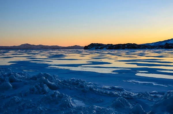 Vista del hielo y el sol naciente sobre las montañas, el lago Baikal — Foto de Stock