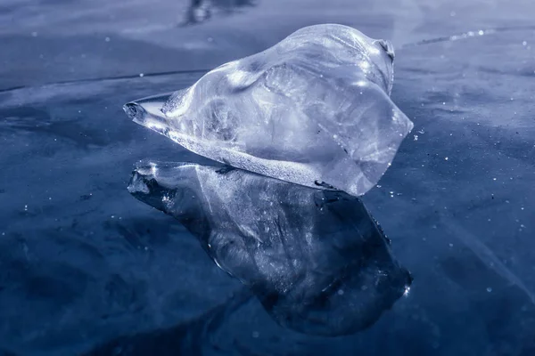 Eisscholle an gefrorener Seeoberfläche mit Spiegelung. Tiefe Risse im Eis und Eisreflexion — Stockfoto