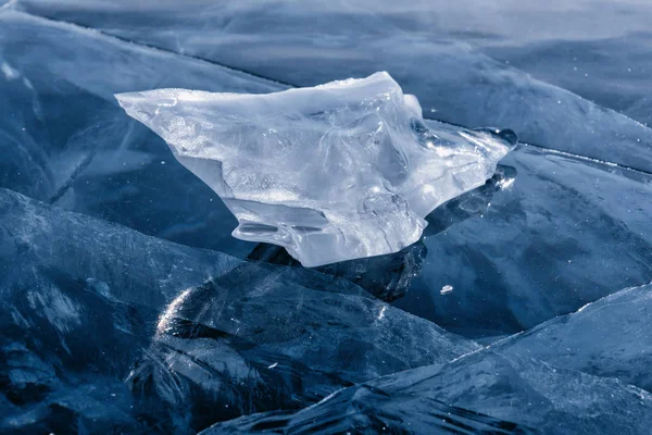 Eisscholle an gefrorener Seeoberfläche mit Spiegelung. Tiefe Risse im Eis und Eisreflexion — Stockfoto