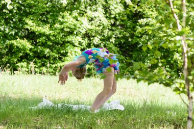 Bir yoga köprü tekerlek poz yeşil çimenlerin üzerinde yapıyor küçük bir kız. Germe ve fitness eğitim yaz çayır üzerinde sağlıklı çocukluk