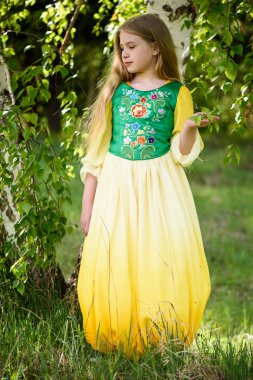 Huş ağaçları yakınındaki bir sarı yeşil giysili poz sarışın genç kız