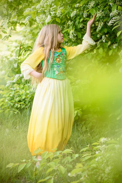 Jeune fille blonde posant dans une robe jaune verte près des bouleaux — Photo