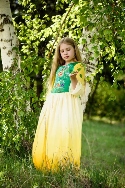 Blondes junges Mädchen posiert in einem gelbgrünen Kleid in der Nähe von Birken — Stockfoto