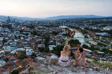 Georgia, Tiflis - Temmuz, 4, 2018. İki kız wathcing Kura Nehri ve Tiflis eski şehir. Gürcistan'da yaz saati görünümünde günbatımı