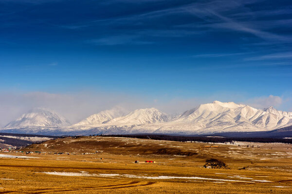 Зимний пейзаж Монголии. Белый горный фон и желтая долина

