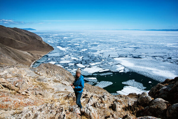 View above big beautiful lake Baikal with Ice floes floating on the water with girl wears blue jacket, Russia