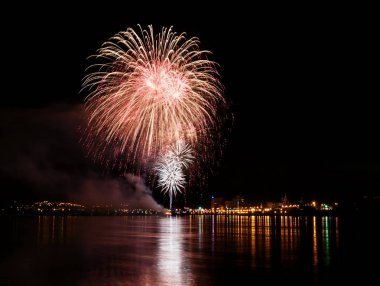 uzun pozlama üzerinde sakin su dalgalanan yansıtan havai fişek