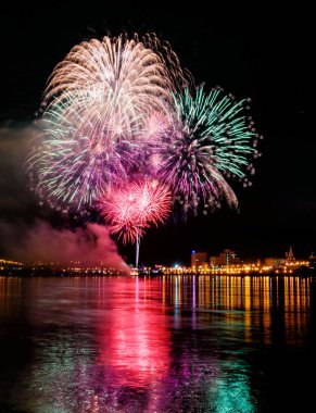 uzun pozlama üzerinde sakin su dalgalanan yansıtan havai fişek