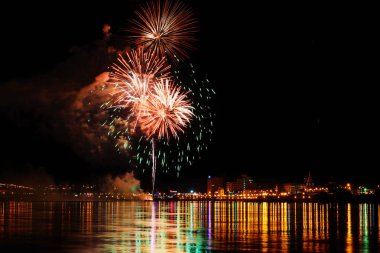 uzun pozlama üzerinde sakin su dalgalanan yansıtan havai fişek