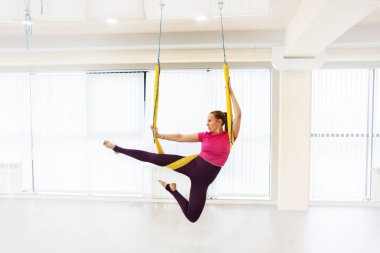 Fit güzel genç kadın fitness eğitim beyaz spor salonu loft sınıfta sinek yoga germe egzersizleri yapıyor spor giyim giyen.