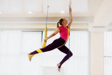 Fit güzel genç kadın fitness eğitim beyaz spor salonu loft sınıfta sinek yoga germe egzersizleri yapıyor spor giyim giyen.