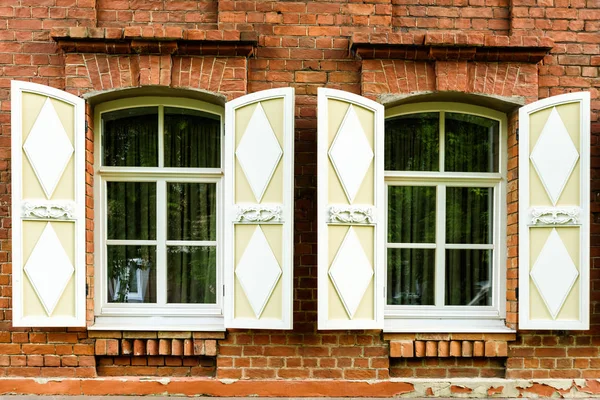 Dos ventanas con el arquitrabe tallado en madera en la antigua casa de madera en el casco antiguo ruso . — Foto de Stock