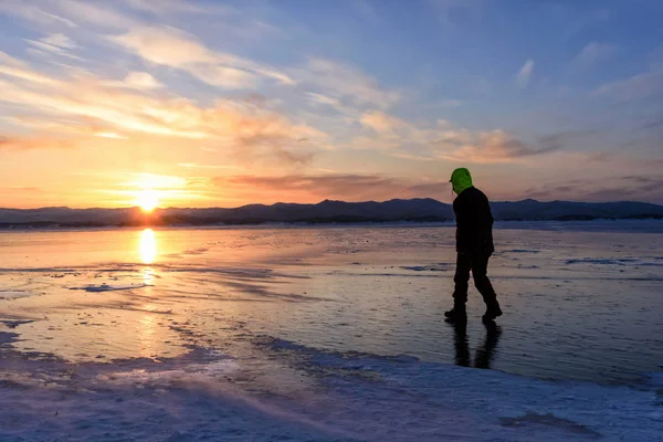 Силуэт человека, идущего по льду на озере Байкал с закатом . — стоковое фото