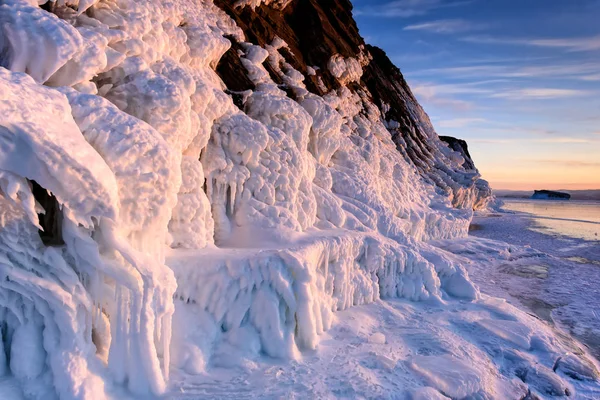 Lago Baikal está cubierto de hielo y nieve, fuerte frío, hielo azul claro grueso. Icicles cuelgan de las rocas. El lago Baikal es un día helado de invierno. Increíble lugar —  Fotos de Stock