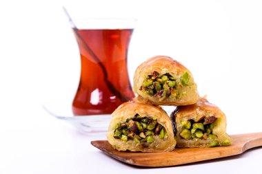 Geleneksel Türk Tatlısı, Antep fıstığı ile ahşap tabakta baklava ve beyaz yüzeyde kaşıkla Türk Çayı.