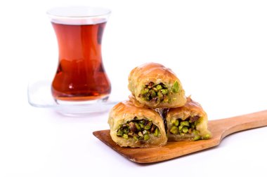 Geleneksel Türk Tatlısı, Antep fıstığı ile ahşap tabakta baklava ve beyaz yüzeyde kaşıkla Türk Çayı.