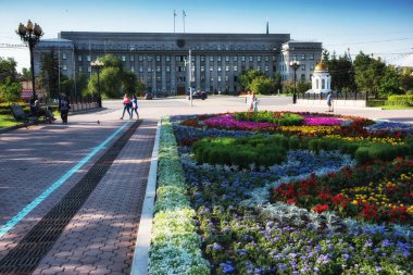 Rusya, Irkutsk - 7 Temmuz 2019: Sovyetler Evi, Irkutsk Bölgesi Hükümeti, Tikhvinsky veya Kirov Meydanı'nda şehir merkezinde çiçek yatağı ve şapel