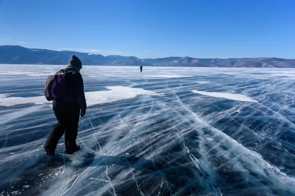 Замороженное озеро Байкал. Два человека силуэты ходить по поверхности льда в морозный день с красивой горой. Естественный фон — стоковое фото
